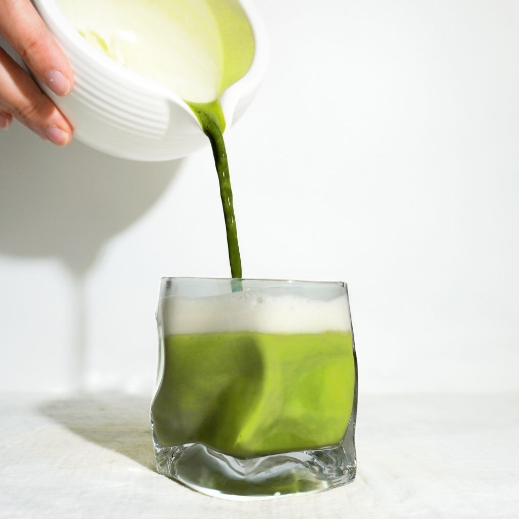 Opgeklopte matcha met schuimlaag in matchakom met bamboe klopper van The Matcha League